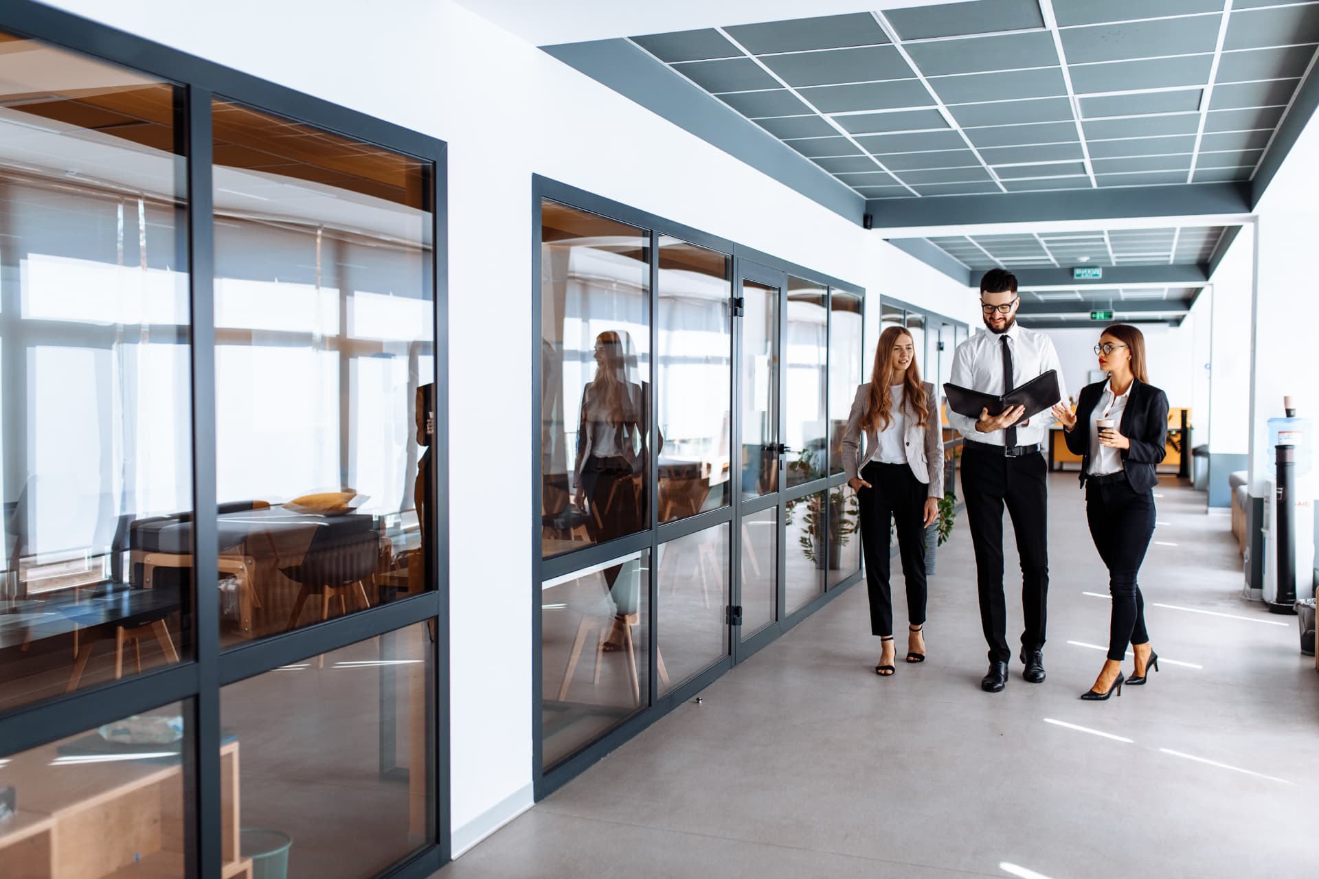 Colleagues walking and talking in a modern office corridor